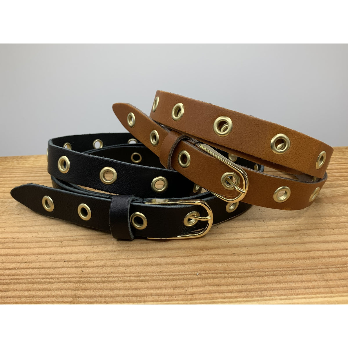 Lange trendy zwarte knoopriem met gouden ringen.