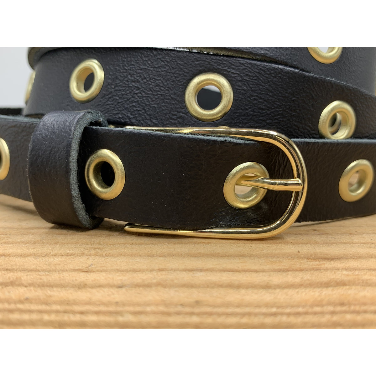 Lange trendy zwarte knoopriem met gouden ringen.